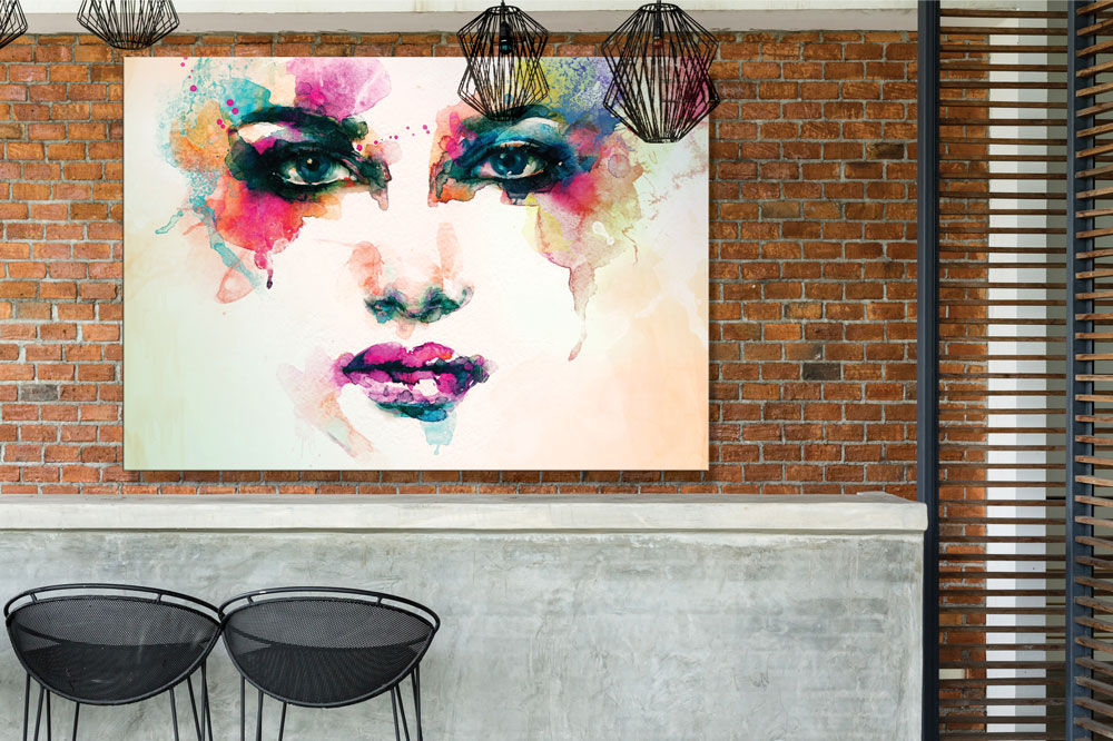 A colorful print of a woman's face hanging on a brick wall behind a cafe counter.